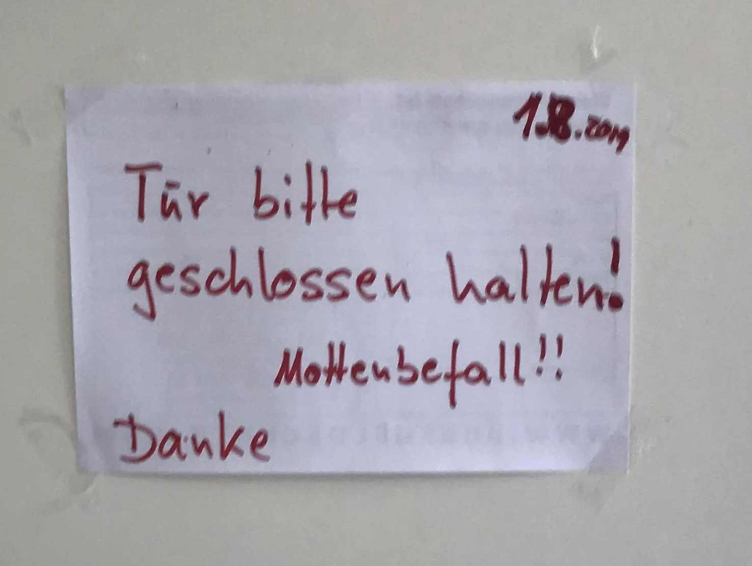 Ein hangeschriebener Zettel: Tür bitte geschlossen halten! Mottenbefall!!! Danke 1.8.2019